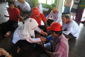 relawan kelurahan belajar mencoba menggunakan alat pengukur tekanan darah